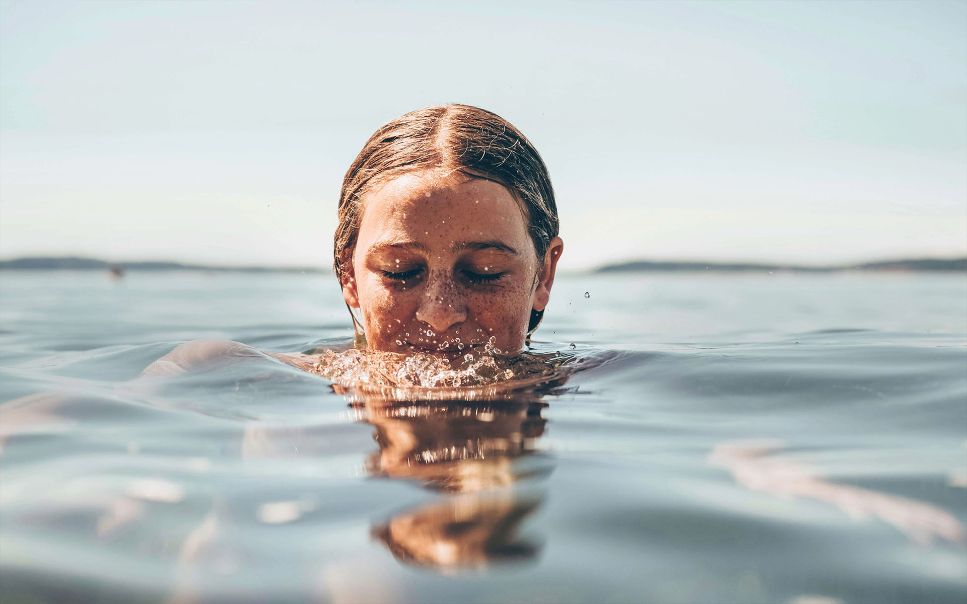 Frau taucht im Wasser auf und genießt Erfrischung