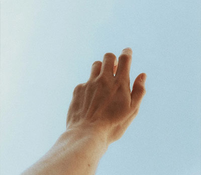 Hand streckt sich achtsam in den Himmel