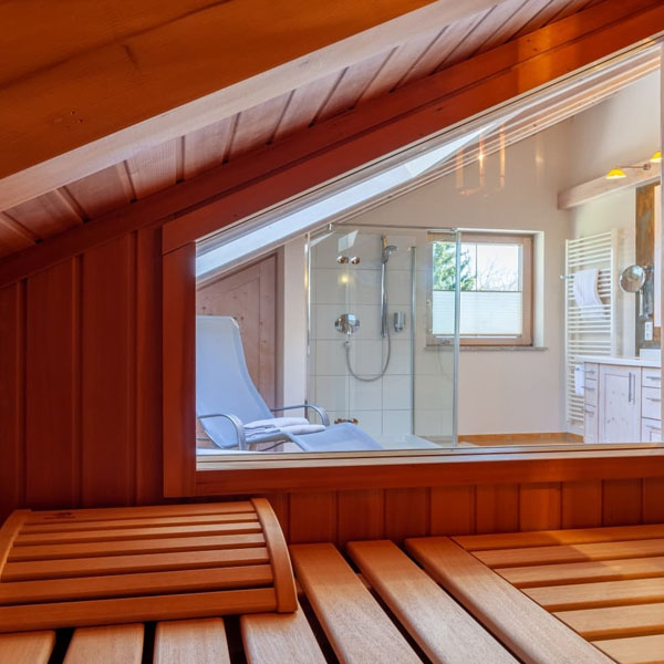 Blick aus der Sauna in ein Badezimmer mit Dusche und Liegestuhl