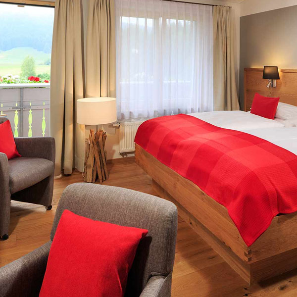 Zimmeransicht mit Bett, Sitzmöbeln und Fenster