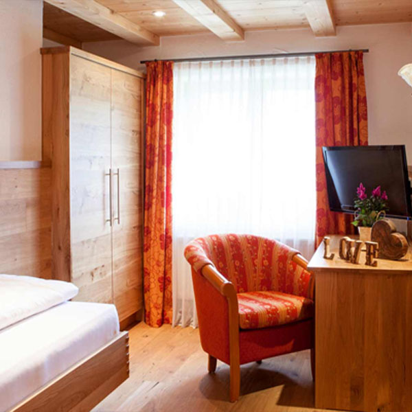 Einzelzimmer mit Bett, Sessel und Fernseher