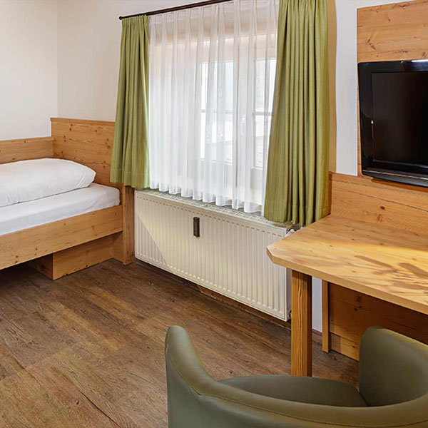 Einzelbett mit Holzrahmen und Dekokissen