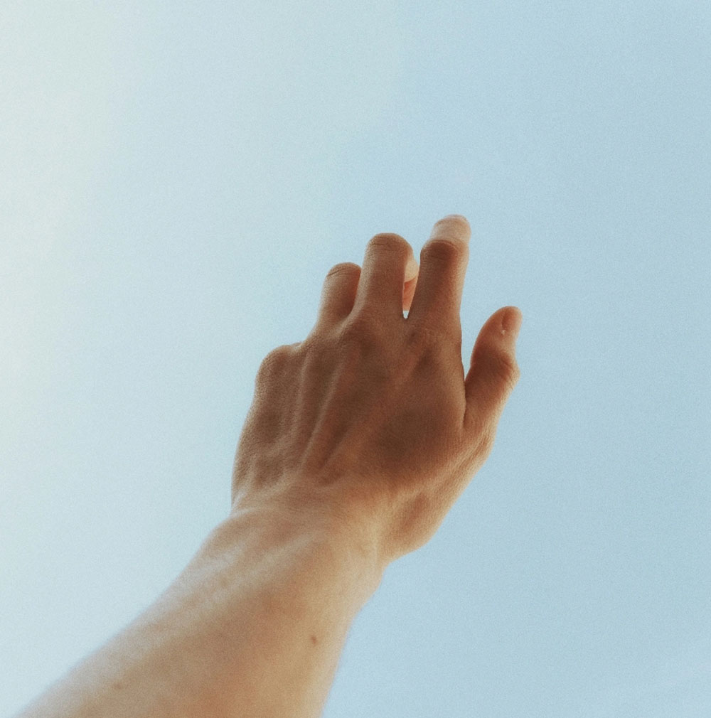 Hand streckt sich in den Himmel als Symbol für Freiheit