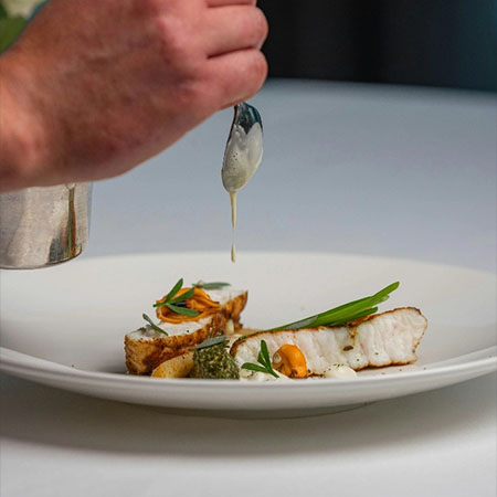 Fischgericht wird mit Sauce angerichtet