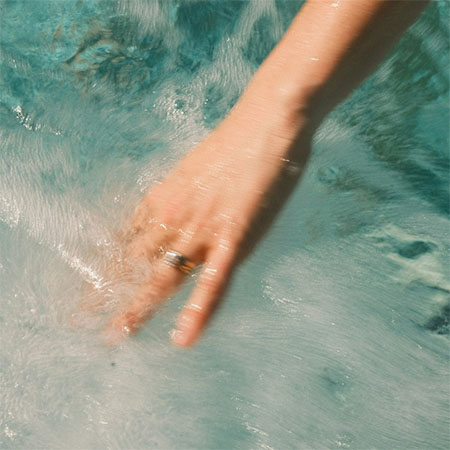 Hand bewegt sich durch sprudelndes Wasser im Spa