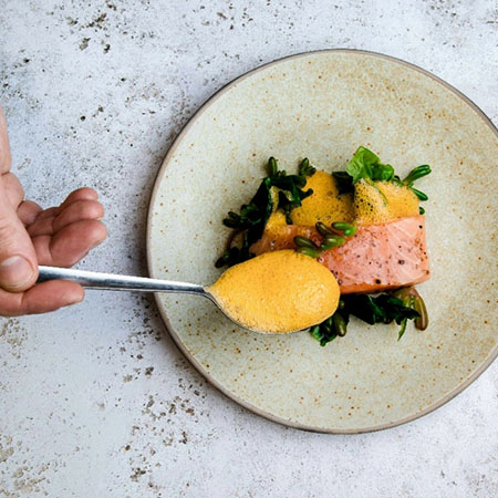 Fischgericht mit Gemüse und Sauce angerichtet