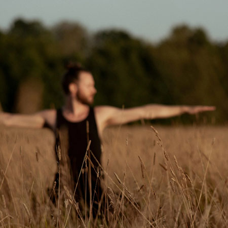 Mann macht Yoga-Übung auf einer Wiese in der Natur