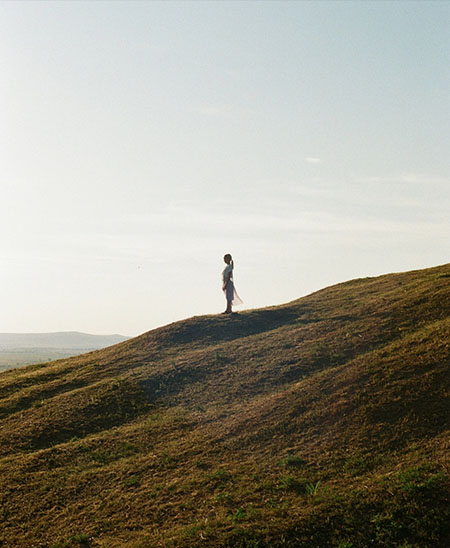 Frau steht auf einem Hügel mit Blick über die Landschaft